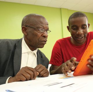Two pastors from Rwanda eagerly browse eVitabu’s library of theological content using a solar-powered Android device Kent charity helps East African pastors find App-iness