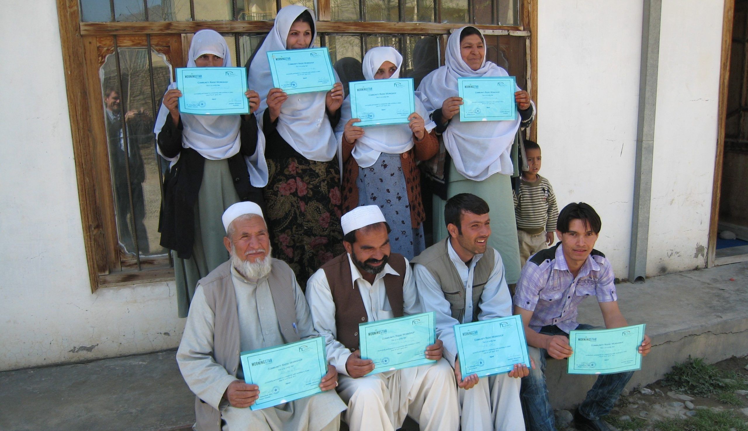 Afghan community health workers proudly displaying their certificates in Community Media after an HCR workshop