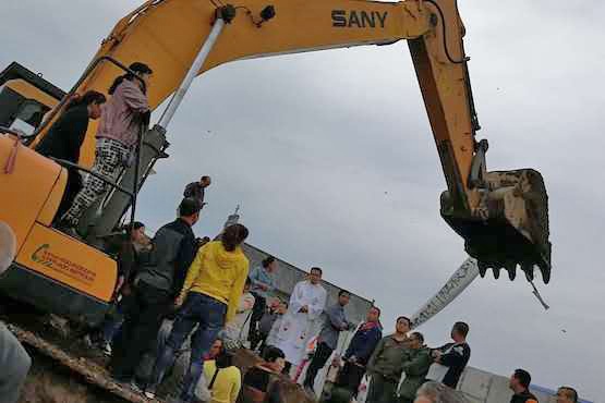 A priest (in white in the picture) and his congregation blocked heavy earthmoving equipment from destroying their church in north China on 28 August, but many were injured in the protest