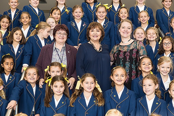 (Adults left to right) Merinda D’Aprano, head of Notre Dame School Cobham, singer Dana and Julie Shaw, head of music. The school’s choir (behind) sang a new version of Dana’s famous Eurovision-winning song All Kinds of Everything at the opening of the Christian Resources Exhibition