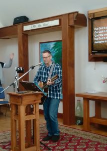 Chris Wickland leading worship at a meeting in March
